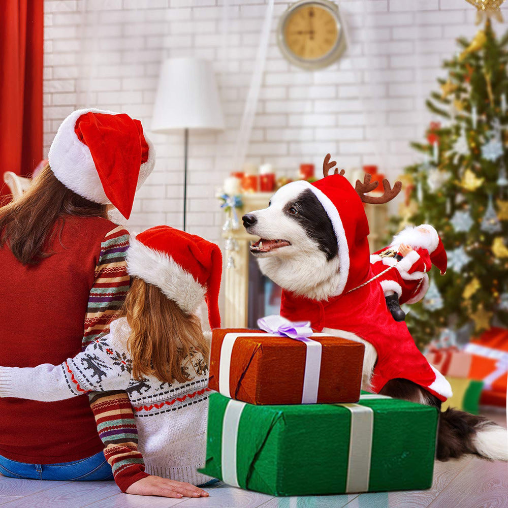 Dog wearing a red Santa Riding Reindeer Christmas costume with two children in Santa hats and gift boxes at a Christmas tree