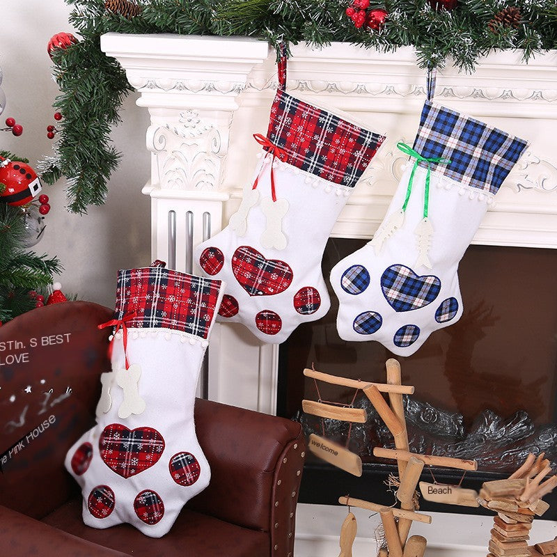 Three dog paw Christmas stockings with plaid tops and paw print design hanging by a fireplace