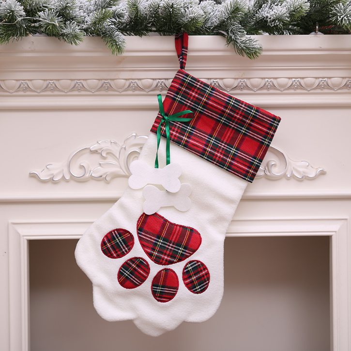 Dog paw Christmas stocking with red tartan cuff and red plaid paw print on a fireplace mantel