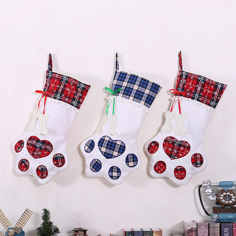 Three white dog paw Christmas stockings with red and blue plaid cuffs and bone decoration