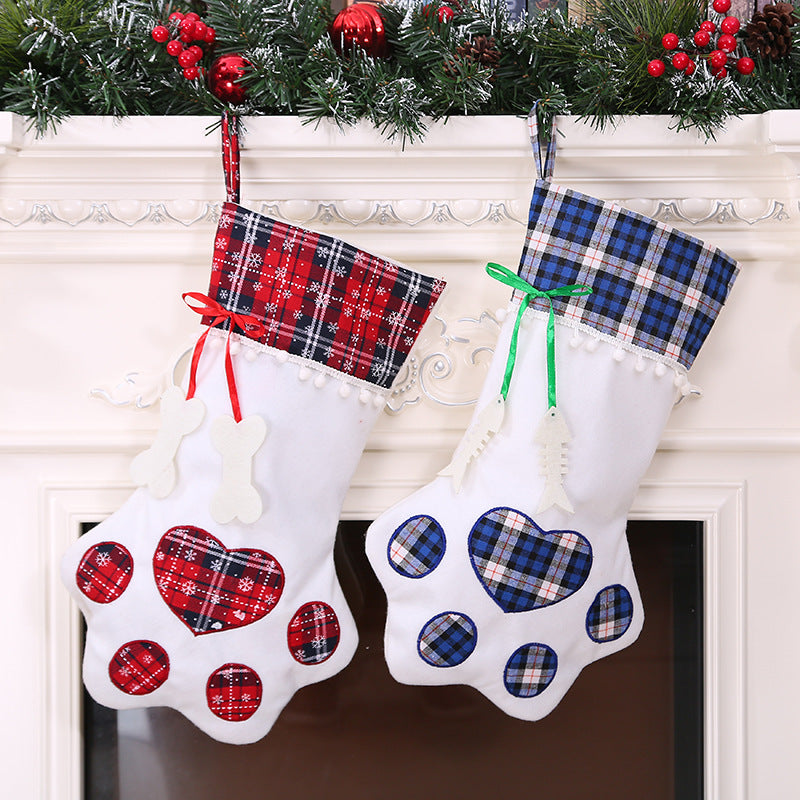 Red and blue plaid dog paw Christmas stockings for treats and gifts hanging on a fireplace mantel