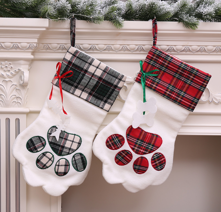Two plaid dog paw Christmas stockings in black and white and red tartan on a mantel